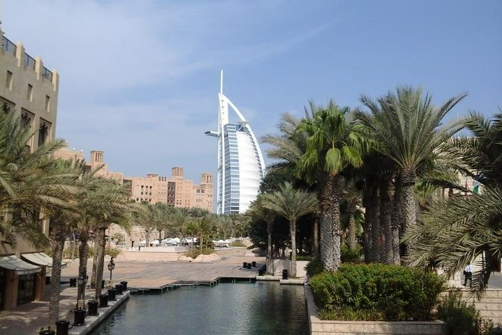 Experience the blend of tradition and modernity in Dubai with stunning views of iconic landmarks like Burj Al Arab amid lush palm trees and serene waterways. Perfect for memorable photos!